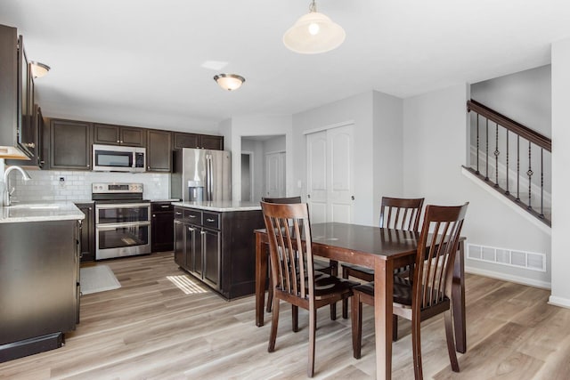 dining room with stairway, baseboards, visible vents, and light wood-type flooring