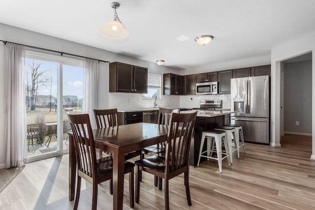 dining area with baseboards and light wood-style flooring