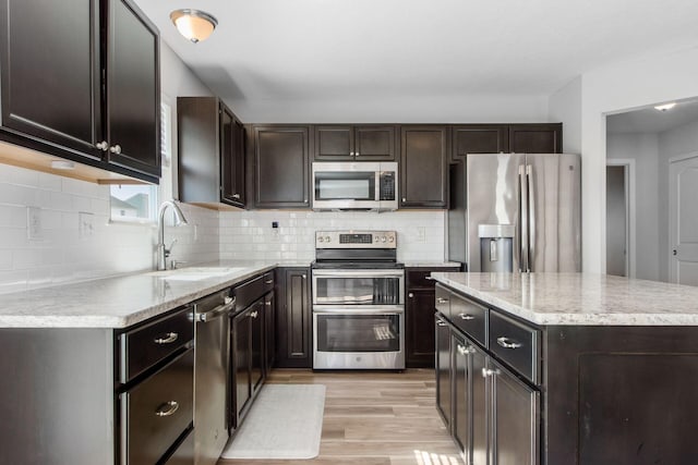 kitchen with light wood-type flooring, a sink, tasteful backsplash, stainless steel appliances, and dark brown cabinetry