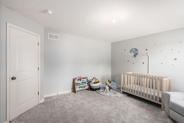 carpeted bedroom featuring visible vents, a crib, and baseboards