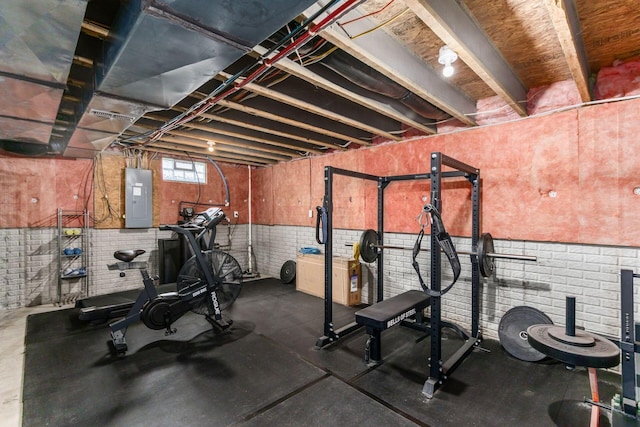 workout room with electric panel, brick wall, and wainscoting