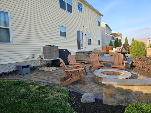 view of patio / terrace with central air condition unit, entry steps, a fire pit, and fence