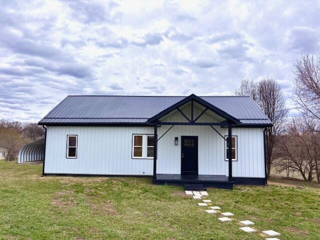 modern farmhouse style home featuring a front lawn and metal roof