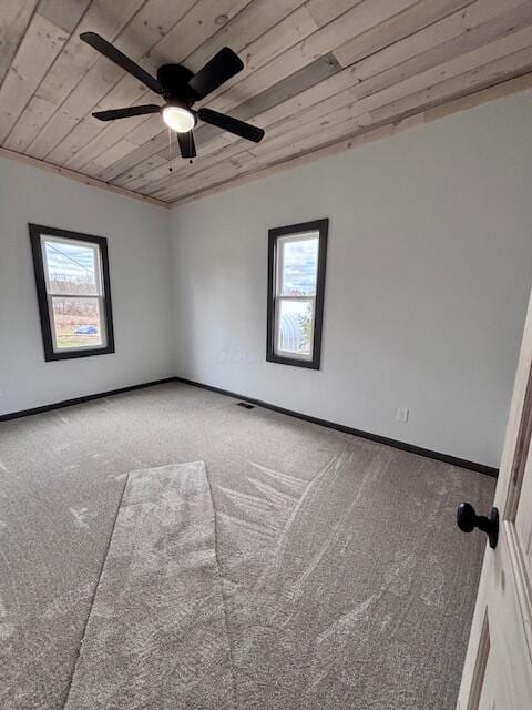 carpeted spare room with a wealth of natural light, baseboards, wood ceiling, and a ceiling fan