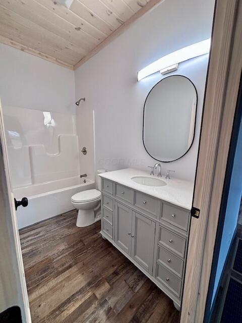 bathroom with toilet, wood finished floors, shower / bathing tub combination, wood ceiling, and vanity