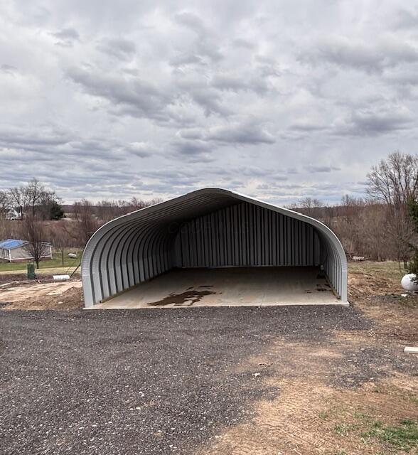 view of parking with a carport and dirt driveway