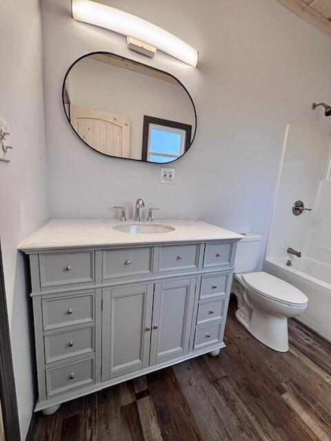 bathroom featuring toilet, vanity,  shower combination, and wood finished floors