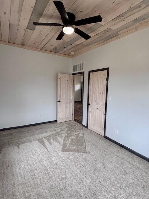 empty room featuring light colored carpet, wood ceiling, baseboards, and ceiling fan