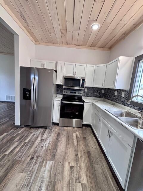 kitchen featuring visible vents, a sink, stainless steel appliances, white cabinets, and wood ceiling