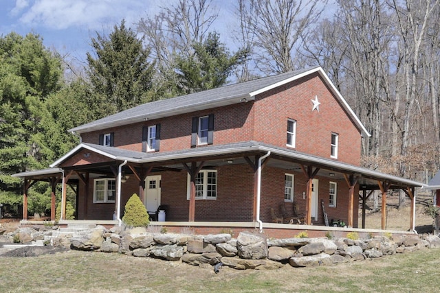 farmhouse inspired home featuring covered porch and brick siding