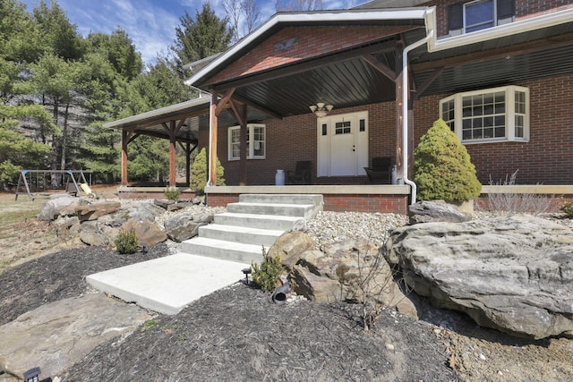 property entrance with brick siding and a porch