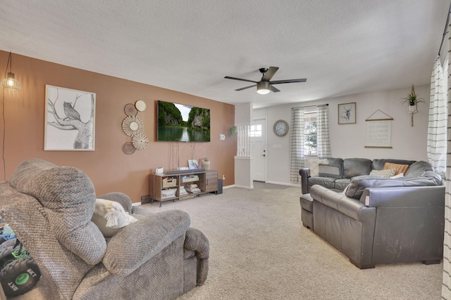 living area with baseboards, carpet floors, a textured ceiling, and ceiling fan