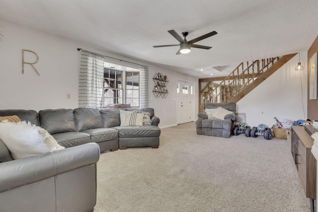 carpeted living room with stairway, a textured ceiling, and a ceiling fan