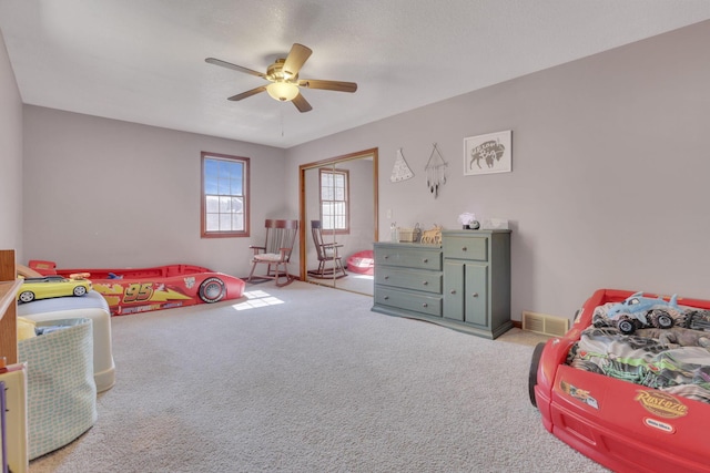 bedroom with a closet, visible vents, ceiling fan, and carpet