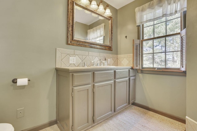 bathroom with baseboards, backsplash, vanity, and toilet