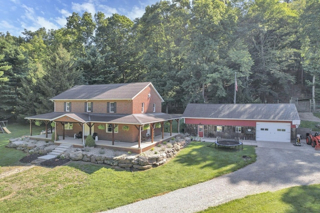 farmhouse-style home featuring brick siding, gravel driveway, a front lawn, a trampoline, and covered porch