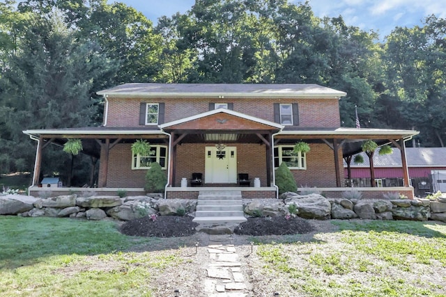 view of front of home with brick siding, covered porch, and a front lawn