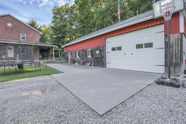 garage with concrete driveway and a trampoline