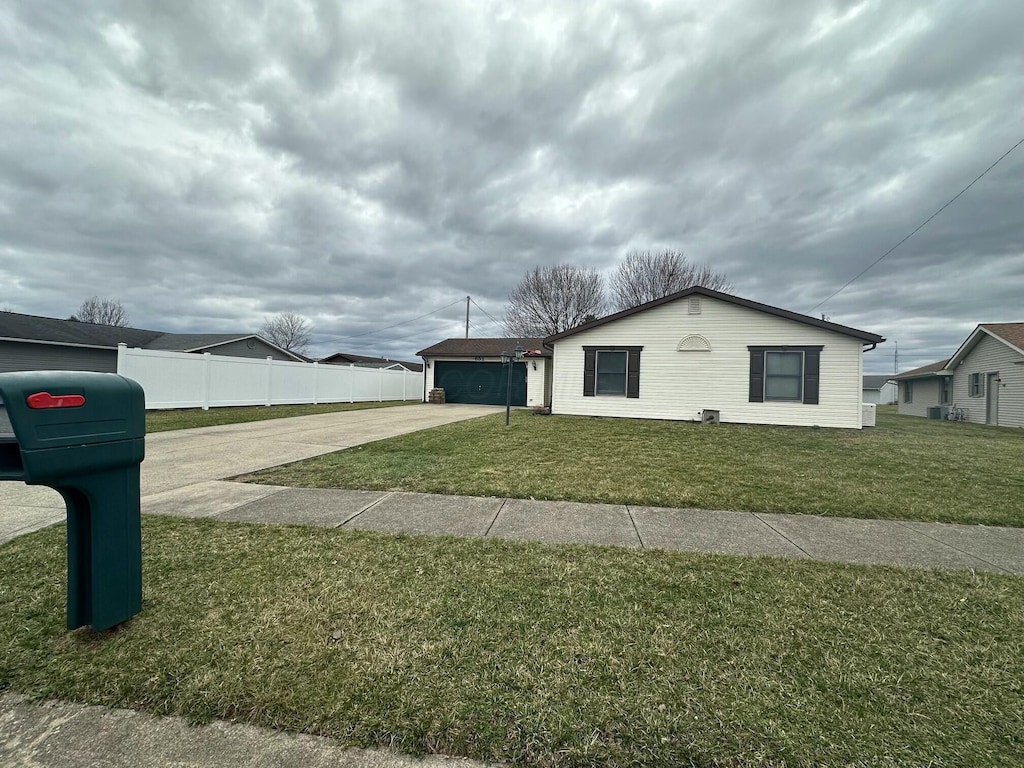 view of side of home featuring a garage, a lawn, fence, and driveway