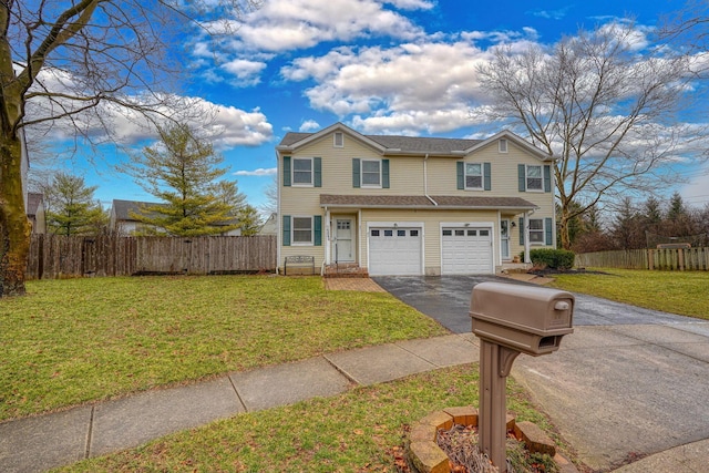 traditional home featuring a garage, a front lawn, driveway, and fence