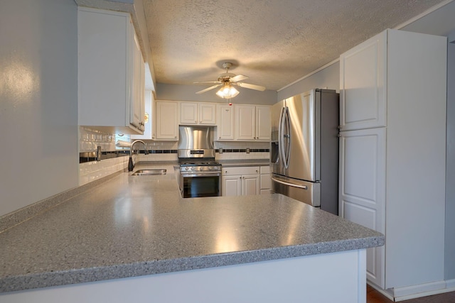 kitchen featuring backsplash, ceiling fan, a peninsula, stainless steel appliances, and a sink