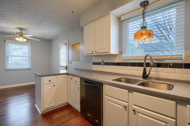 kitchen with a peninsula, dark wood-style flooring, a sink, black dishwasher, and backsplash