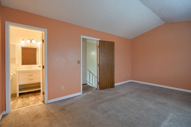 unfurnished bedroom with lofted ceiling, carpet, baseboards, and a textured ceiling