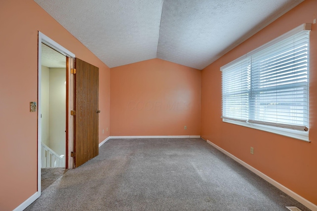 unfurnished room with a textured ceiling, baseboards, carpet, and vaulted ceiling