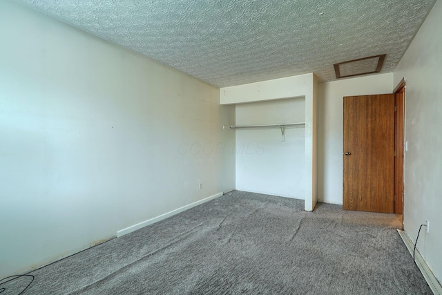 unfurnished bedroom featuring a closet, carpet, attic access, and a textured ceiling