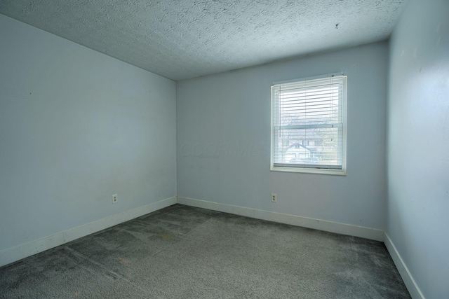 carpeted empty room with baseboards and a textured ceiling