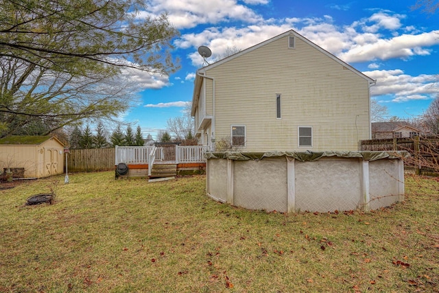 exterior space with a covered pool, fence, a wooden deck, a storage shed, and a yard