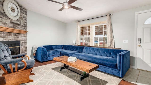 living room featuring a fireplace, a ceiling fan, and wood finished floors