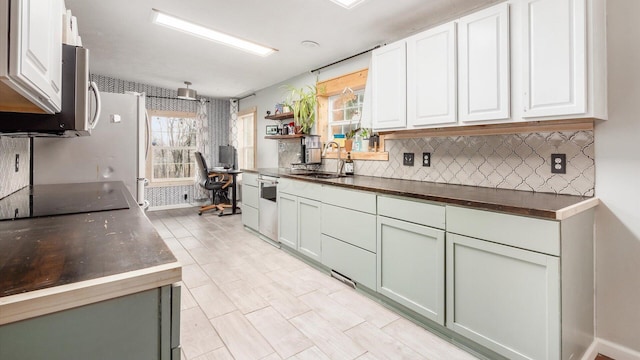 kitchen with a sink, dishwasher, white cabinetry, black electric cooktop, and backsplash