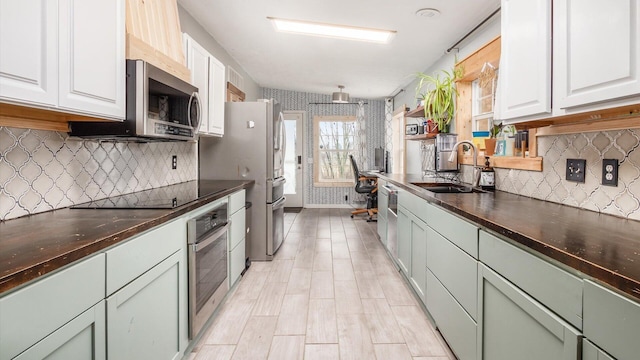 kitchen featuring a sink, stainless steel appliances, dark countertops, and wallpapered walls