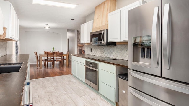 kitchen with light wood-style floors, backsplash, appliances with stainless steel finishes, and white cabinetry