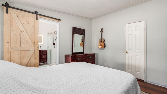 bedroom with connected bathroom, a barn door, and dark wood-style flooring