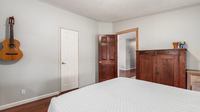 bedroom featuring crown molding, dark wood-style floors, baseboards, and a textured ceiling