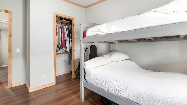 bedroom featuring a closet, ornamental molding, baseboards, and wood finished floors