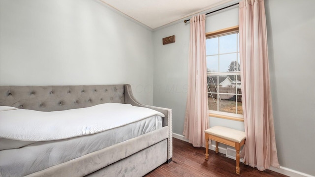 bedroom featuring ornamental molding, baseboards, and wood finished floors