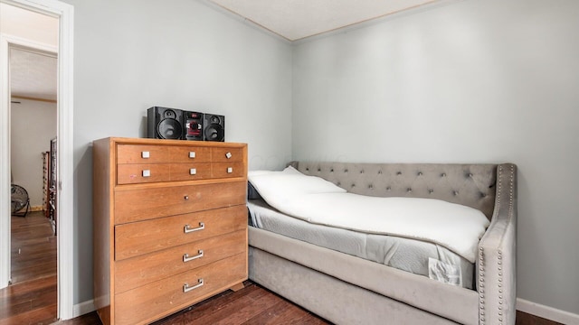 bedroom with dark wood finished floors, crown molding, and baseboards