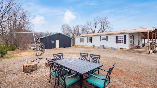 rear view of house with outdoor dining space, an outdoor structure, and metal roof