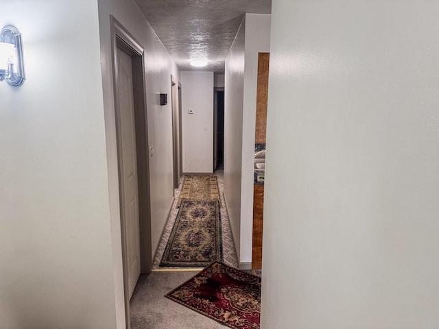 corridor featuring a textured ceiling and carpet flooring