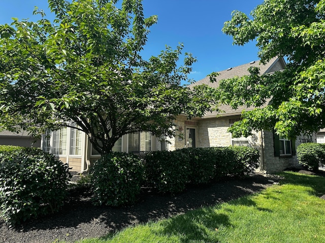 4163 Windbud Dr, New Albany, OH 43054 - view of side of property featuring stone siding, a lawn, and a shingled roof