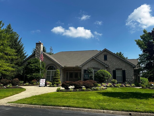 4163 Windbud Dr, New Albany, OH 43054 - view of front of home featuring stone siding, a front lawn, a chimney, and driveway