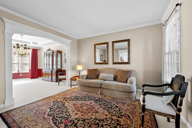 living room with carpet floors, a chandelier, crown molding, and ornate columns