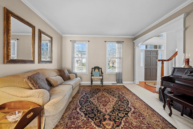 carpeted living room featuring crown molding, decorative columns, and baseboards