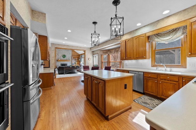 kitchen featuring light wood-type flooring, stainless steel appliances, light countertops, open floor plan, and a center island