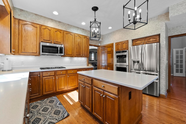 kitchen with appliances with stainless steel finishes, a chandelier, and brown cabinetry