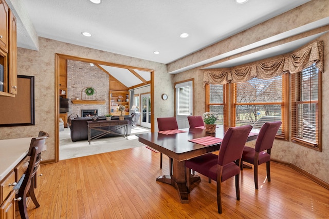 dining area featuring recessed lighting, baseboards, light wood-type flooring, and a large fireplace