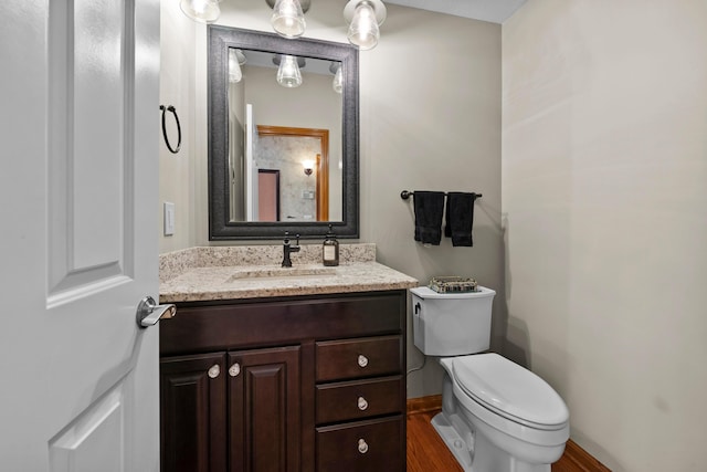 bathroom featuring toilet, vanity, baseboards, and wood finished floors